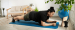 Seorang wanita sedang melakukan plank di atas matras biru sebagai bagian dari workout mengecilkan perut di rumah